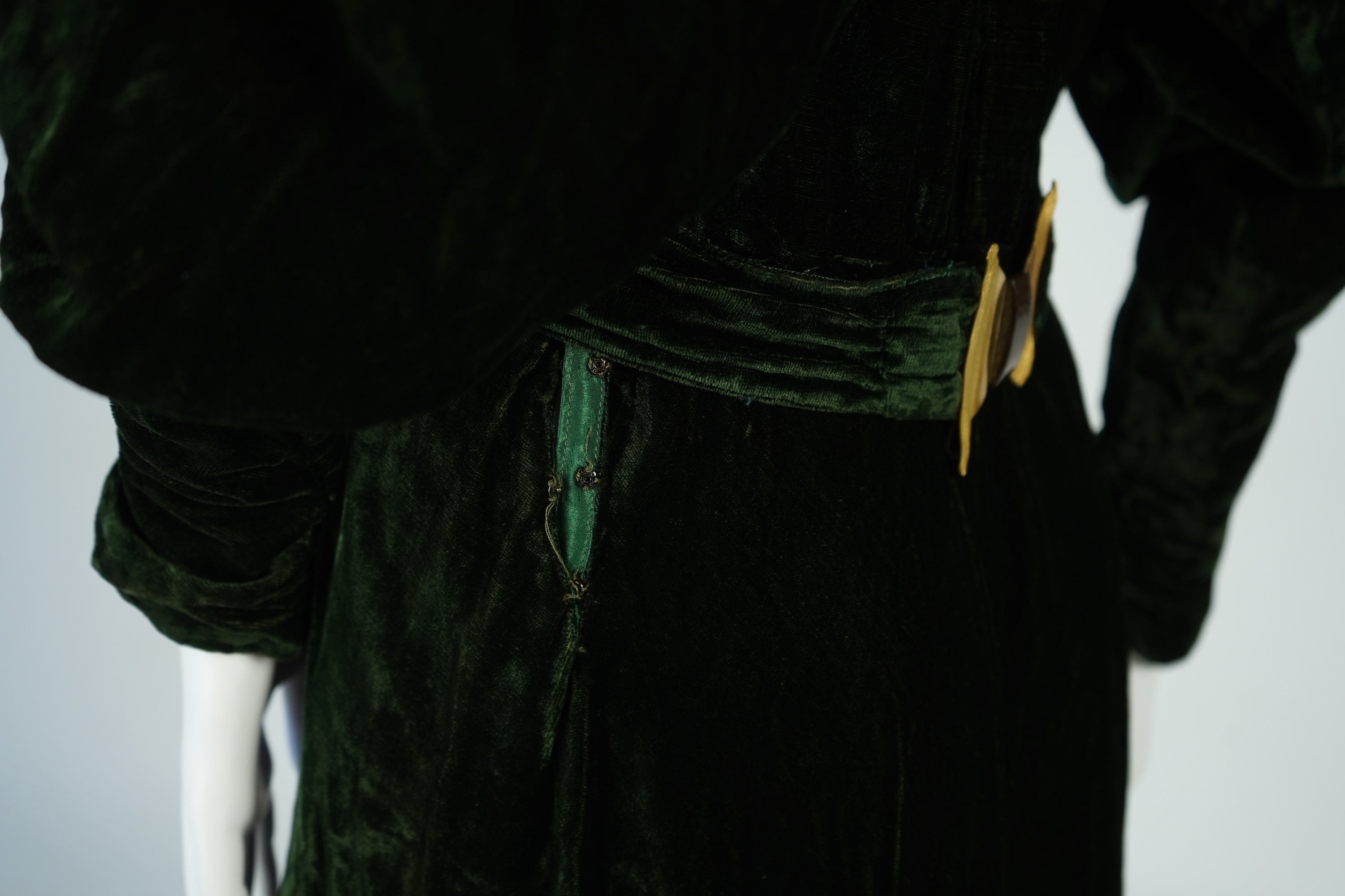 A flesh coloured 1930s lace evening dress and matching jacket together with a bottle green velvet evening dress and buckle belt and an unusual green shot silk pleated under skirt. Lace dress bust 32 inches. 156cm long. C